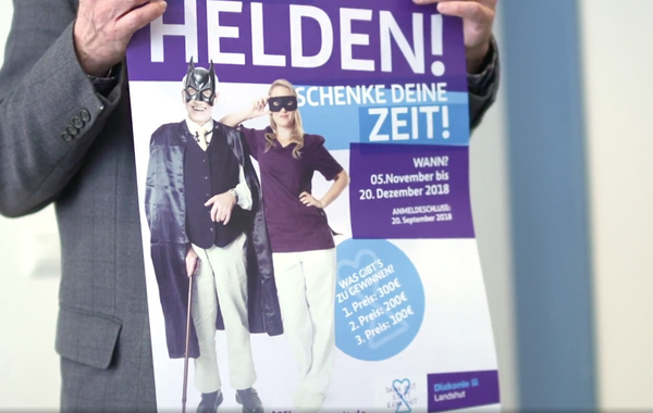 Das Bild zeigt eine Person die ein Poster der Diakonie Landshut in den Händen hält