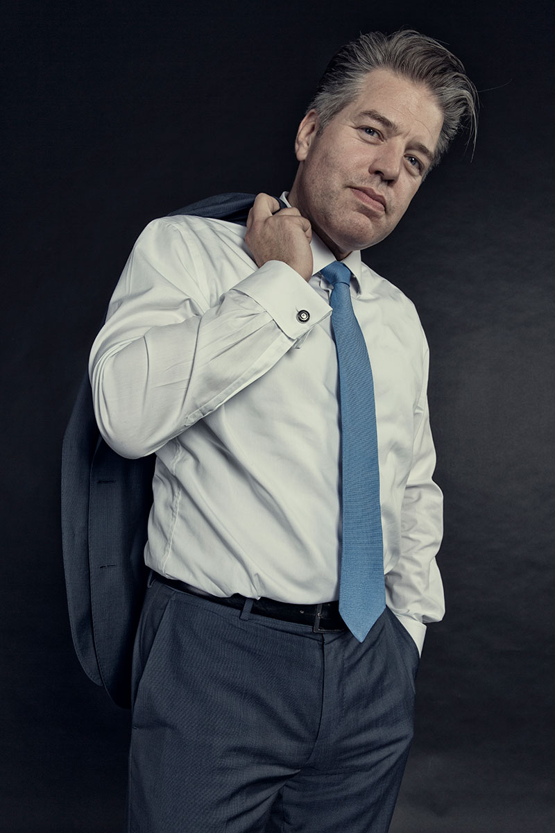 Mann in eleganter Kleidung hat sein Jacket geschultert.